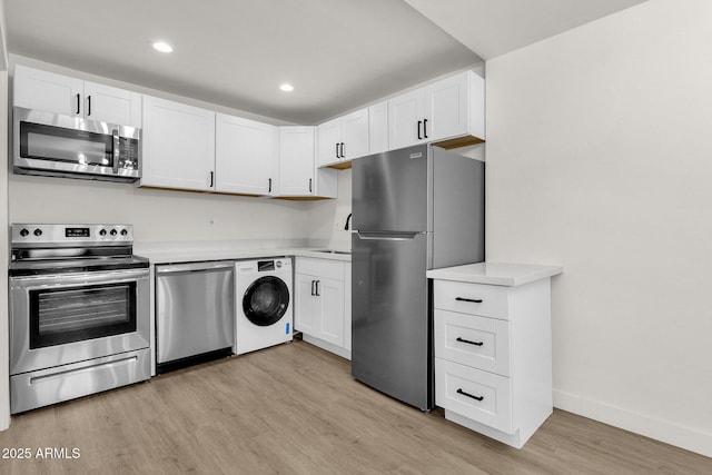 kitchen featuring white cabinets, washer / dryer, light wood-type flooring, and stainless steel appliances