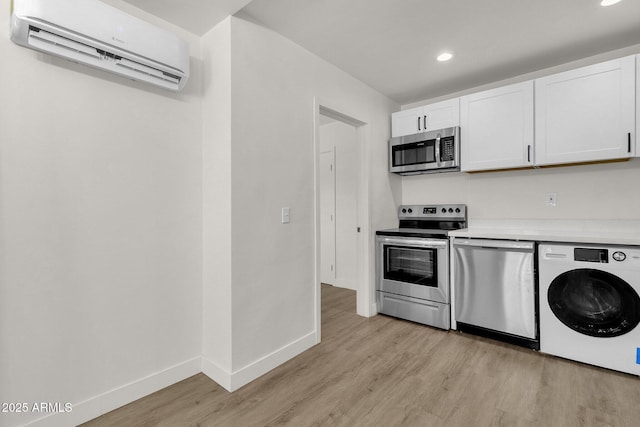 kitchen featuring white cabinetry, stainless steel appliances, a wall unit AC, washer / clothes dryer, and light wood-type flooring