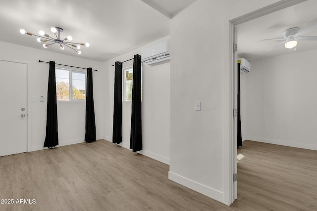 interior space with a wall mounted AC, light hardwood / wood-style flooring, and ceiling fan with notable chandelier