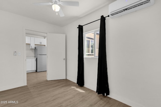 spare room featuring light hardwood / wood-style flooring, an AC wall unit, and ceiling fan