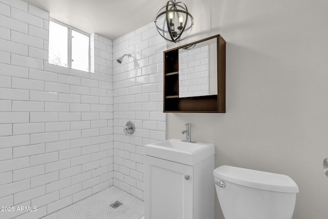 bathroom with tiled shower, vanity, and toilet