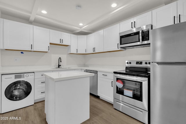 kitchen featuring sink, a kitchen island, washer / dryer, white cabinetry, and stainless steel appliances