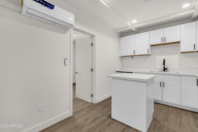 kitchen with white cabinetry, sink, light hardwood / wood-style flooring, an AC wall unit, and a kitchen island