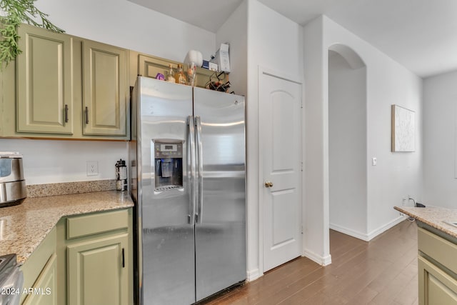 kitchen featuring light stone countertops, green cabinetry, appliances with stainless steel finishes, and dark hardwood / wood-style flooring