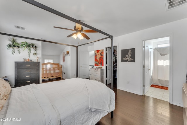 bedroom featuring ceiling fan, a closet, connected bathroom, dark hardwood / wood-style flooring, and a walk in closet