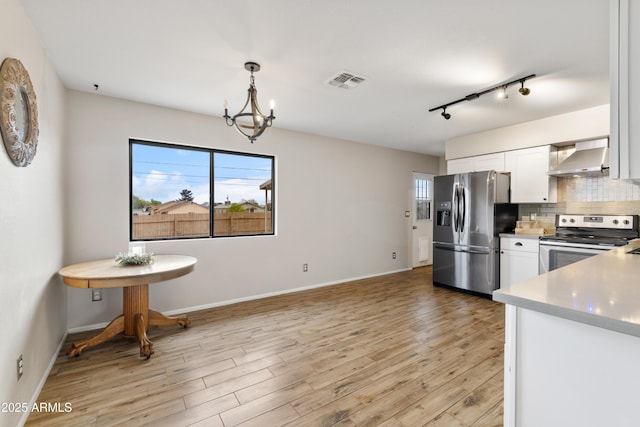 4365 N Tonto Way, Prescott Valley, AZ 86314 - kitchen with appliances with stainless steel finishes, wall chimney range hood, tasteful backsplash, white cabinetry, and rail lighting