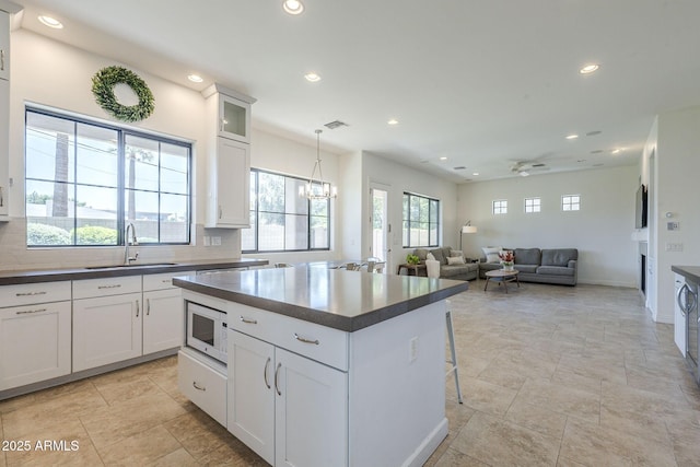 3812 E Camelback Rd, Phoenix, AZ 85018 - kitchen with white microwave, a sink, recessed lighting, dark countertops, and a kitchen island