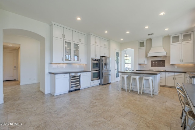 3812 E Camelback Rd, Phoenix, AZ 85018 - kitchen featuring stainless steel appliances, custom range hood, arched walkways, wine cooler, and dark countertops