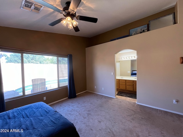 bedroom with ceiling fan, ensuite bathroom, and light carpet