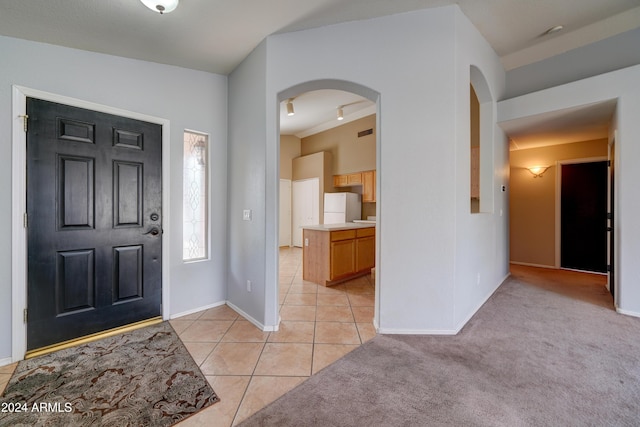 entryway with light tile patterned floors, baseboards, visible vents, and arched walkways