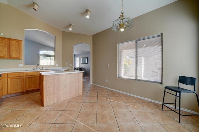 kitchen with light tile patterned floors, a sink, arched walkways, light countertops, and lofted ceiling