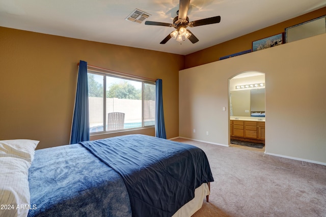 bedroom featuring a ceiling fan, baseboards, ensuite bath, visible vents, and light carpet