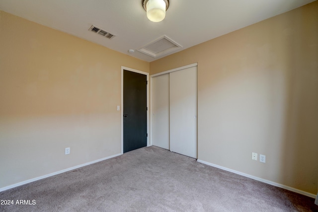 unfurnished bedroom with a closet, attic access, visible vents, carpet flooring, and baseboards