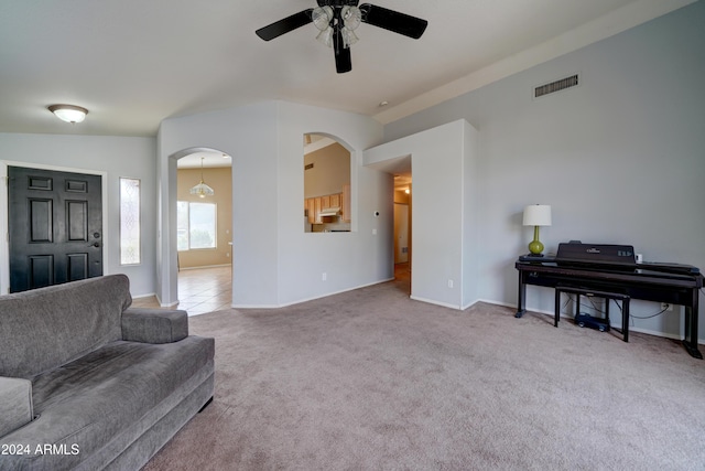 living room featuring carpet, baseboards, visible vents, ceiling fan, and arched walkways
