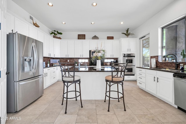 3335 W Carriage Dr, Phoenix, AZ 85086 - kitchen featuring a sink, appliances with stainless steel finishes, a kitchen breakfast bar, dark countertops, and decorative backsplash
