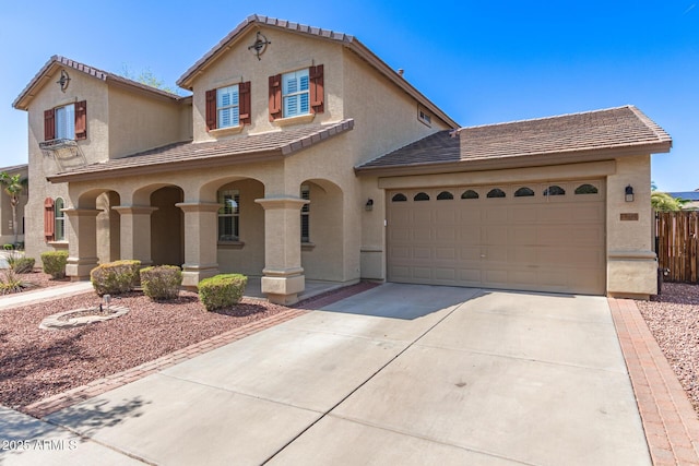 mediterranean / spanish house with stucco siding, driveway, a tiled roof, and an attached garage
