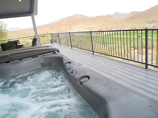 wooden deck with a hot tub and a mountain view