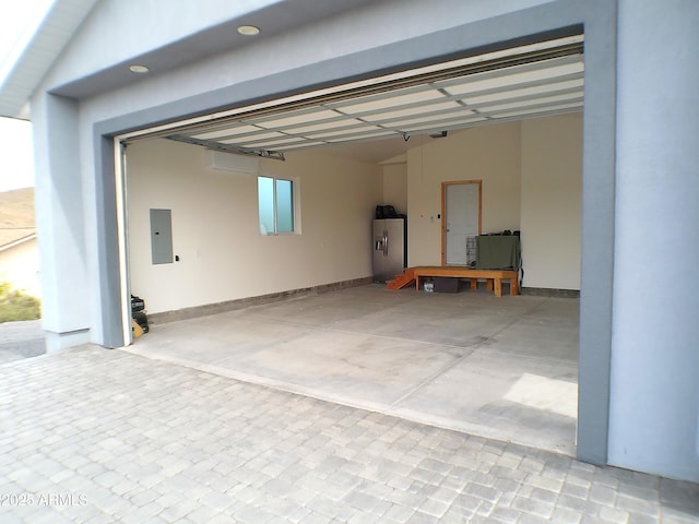 garage featuring stainless steel fridge, electric panel, and decorative driveway