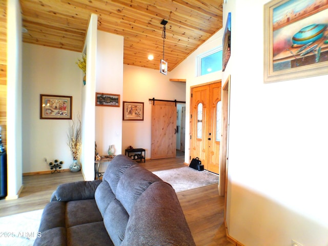 living area with a barn door, wood ceiling, wood finished floors, high vaulted ceiling, and baseboards