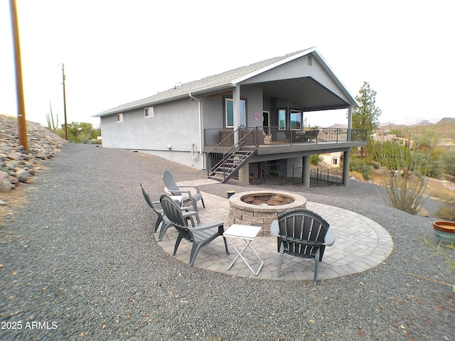 back of house featuring a deck, a patio, an outdoor fire pit, stairway, and stucco siding