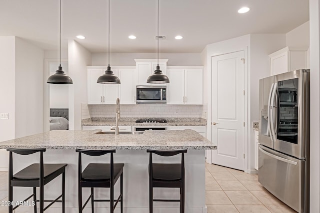 kitchen with appliances with stainless steel finishes, a breakfast bar, backsplash, a center island with sink, and recessed lighting