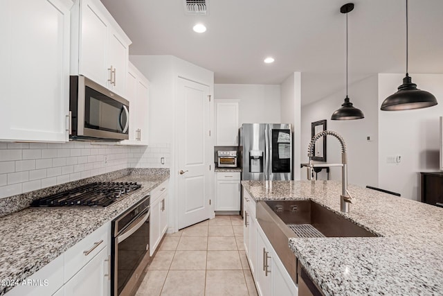 kitchen featuring appliances with stainless steel finishes, a sink, tasteful backsplash, white cabinetry, and hanging light fixtures
