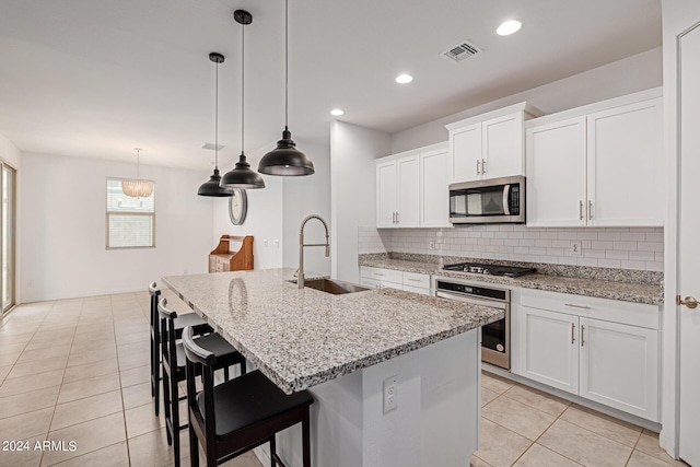 kitchen featuring appliances with stainless steel finishes, a sink, tasteful backsplash, light tile patterned floors, and white cabinetry