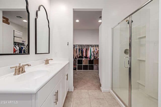 bathroom featuring tile patterned flooring, a shower stall, a walk in closet, and double vanity