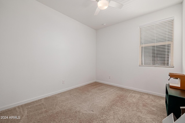 carpeted spare room featuring ceiling fan and baseboards