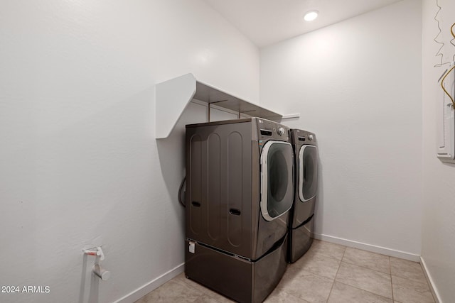 clothes washing area featuring separate washer and dryer, baseboards, and light tile patterned floors
