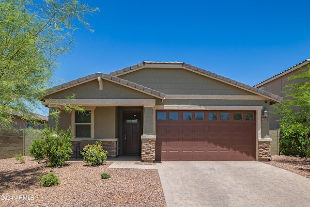 view of front of house with a garage, a tile roof, decorative driveway, and stone siding