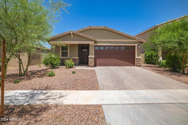 view of front of house with stone siding, decorative driveway, an attached garage, and a tiled roof