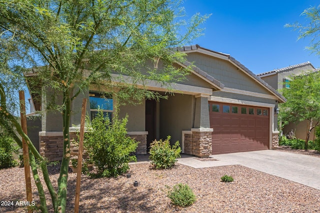 craftsman-style house featuring stone siding, a garage, and driveway