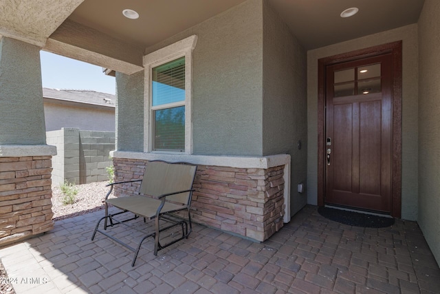 doorway to property with stucco siding and stone siding