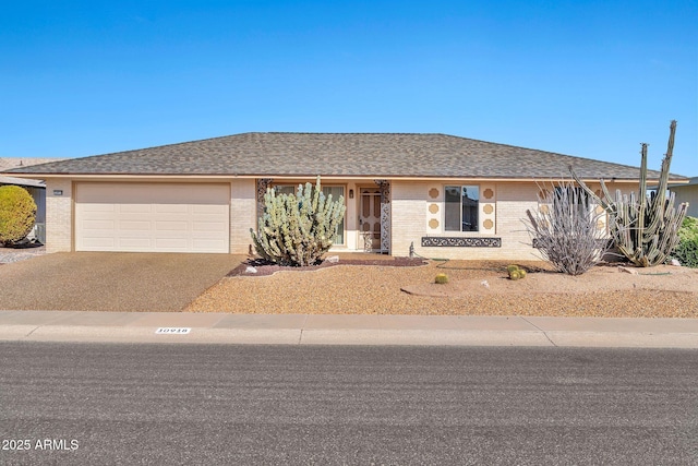 ranch-style home with a garage, brick siding, driveway, and a shingled roof