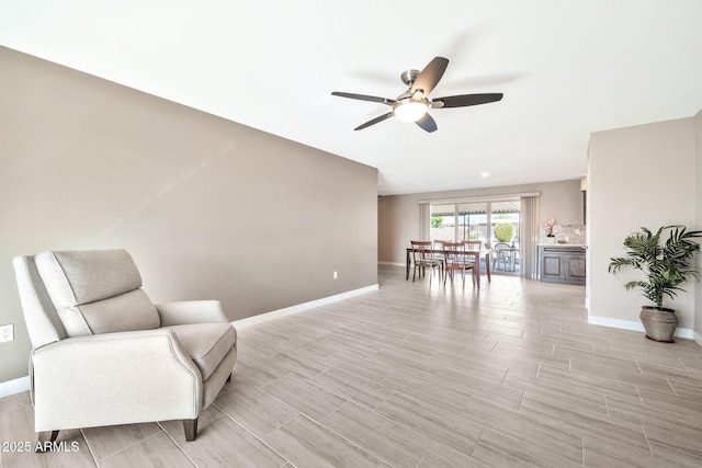 sitting room featuring wood finish floors, a ceiling fan, and baseboards