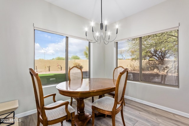 dining area featuring a chandelier, a wealth of natural light, light wood-type flooring, and baseboards