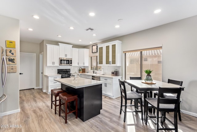 kitchen with visible vents, white cabinets, a center island, stainless steel appliances, and light countertops