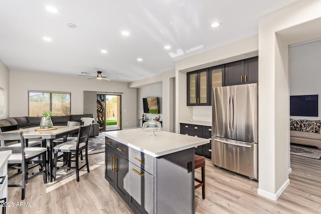 kitchen with a center island, light countertops, glass insert cabinets, freestanding refrigerator, and open floor plan