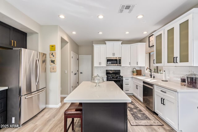 kitchen featuring a sink, visible vents, a kitchen breakfast bar, appliances with stainless steel finishes, and tasteful backsplash