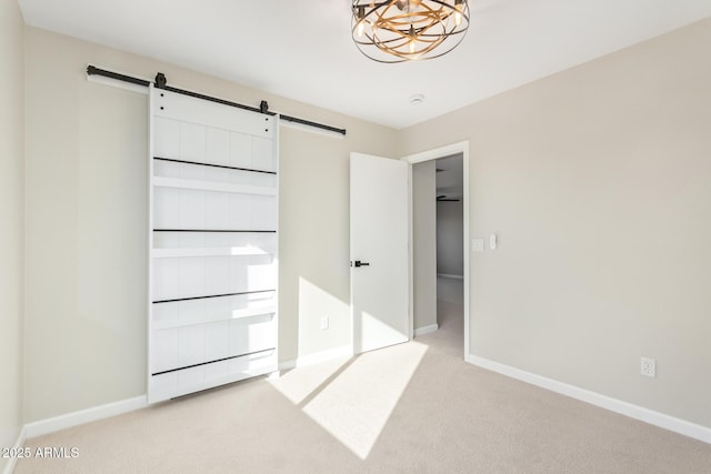 unfurnished bedroom featuring carpet floors, a chandelier, baseboards, and a barn door