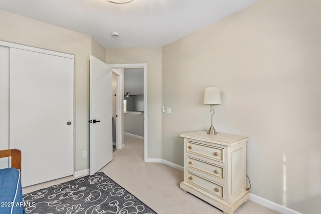 bedroom featuring baseboards, a closet, and light colored carpet