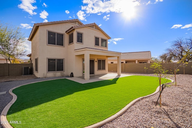 rear view of property with a fenced backyard, a yard, a tiled roof, stucco siding, and a patio area