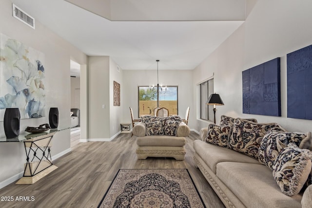 living room featuring baseboards, visible vents, a chandelier, and wood finished floors