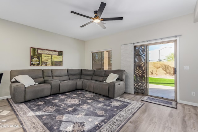 living area featuring a ceiling fan, baseboards, and wood finished floors