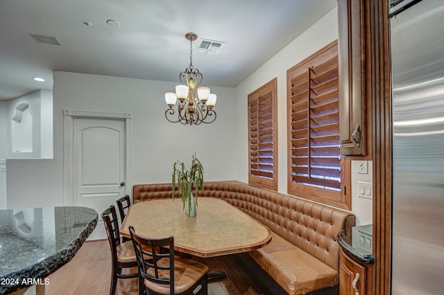 dining space with wood-type flooring and an inviting chandelier