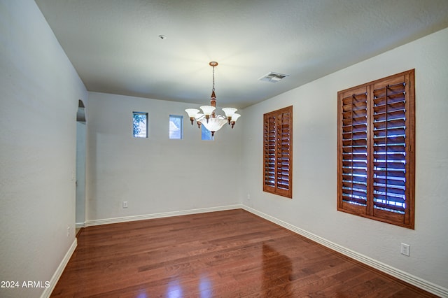 empty room with a notable chandelier and hardwood / wood-style flooring