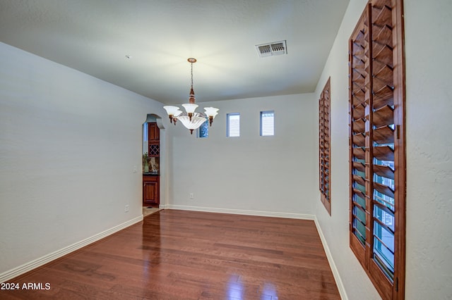 spare room featuring hardwood / wood-style floors and a chandelier