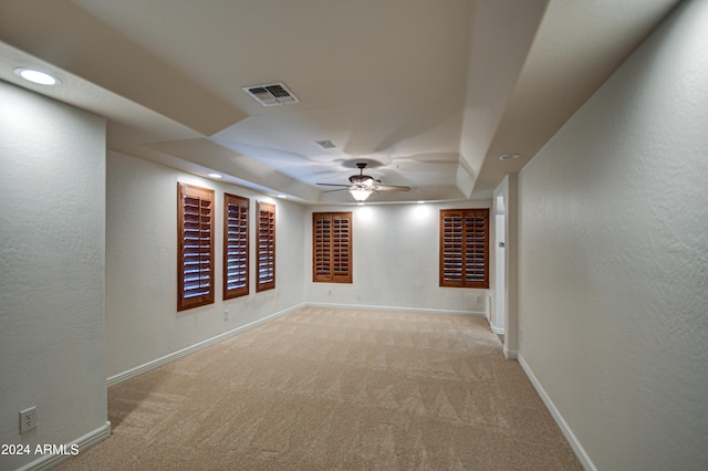 carpeted spare room with ceiling fan and a tray ceiling