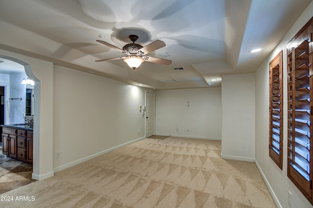 unfurnished room with light colored carpet, sink, and ceiling fan